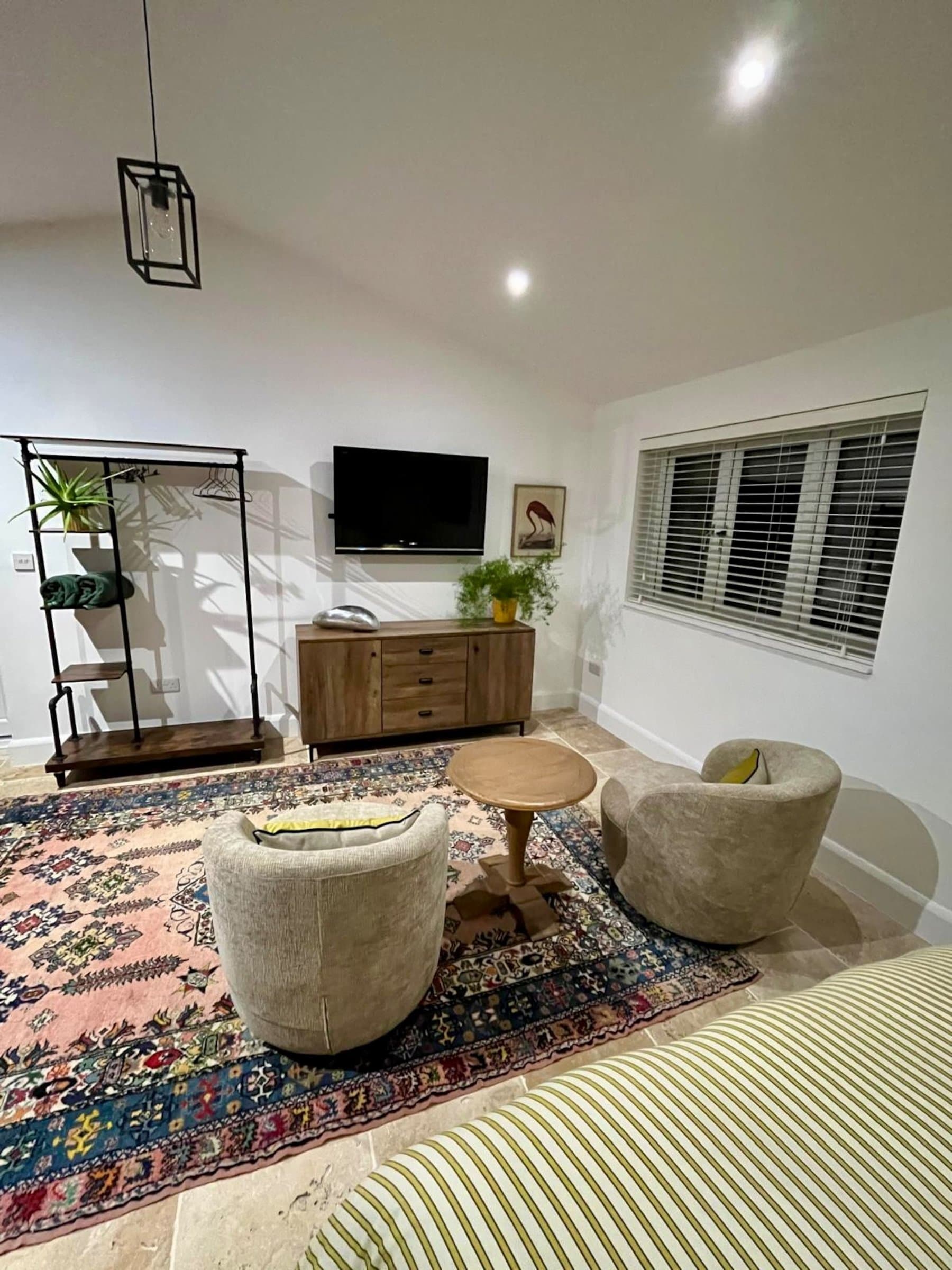 The studio's sitting area: two swivel chairs on a patterned rug under a vaulted white ceiling