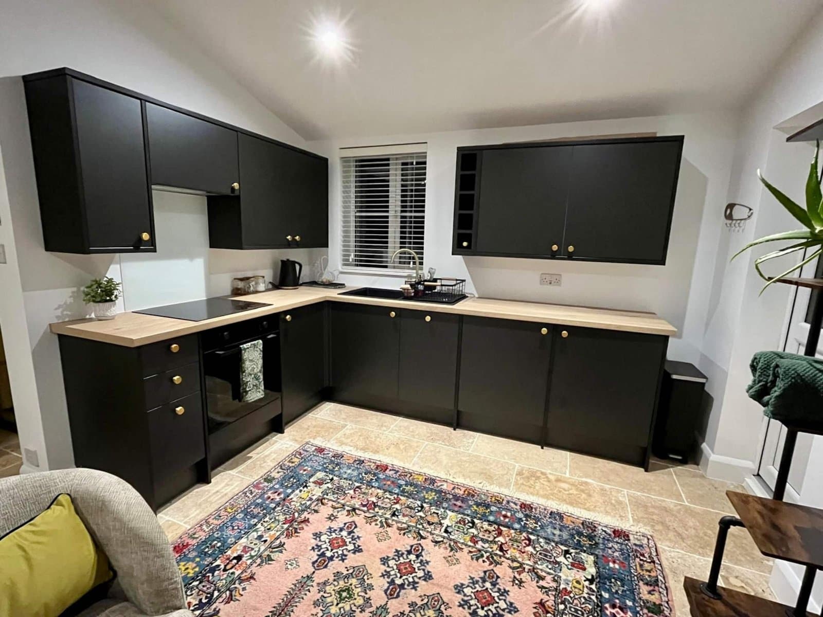 The kitchen, with matt black cabinets, brass handles and an oak worktop